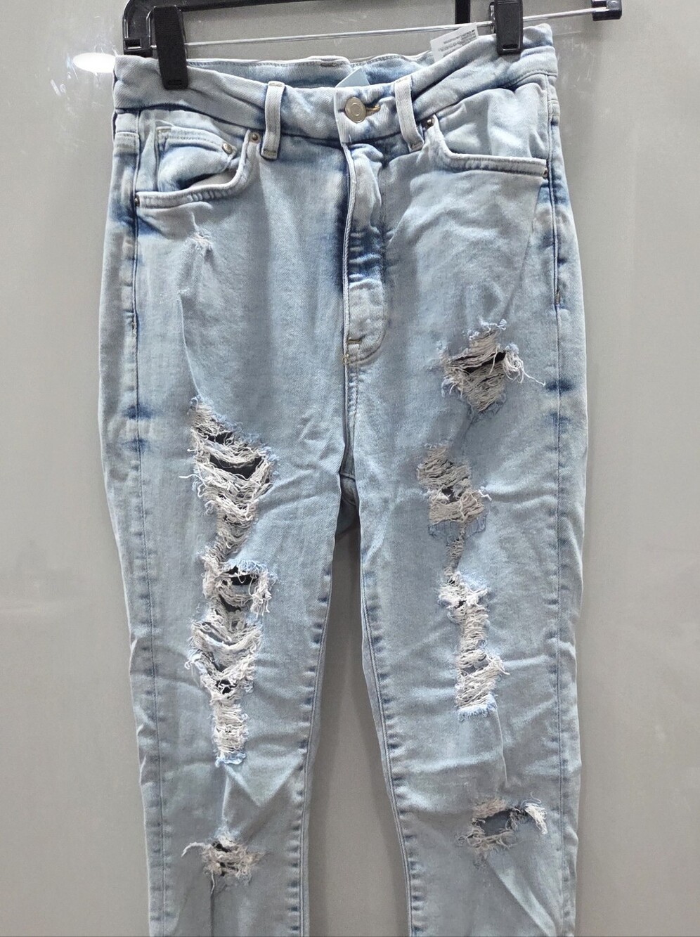 light-wash, heavily distressed super skinny jeans featuring prominent rips